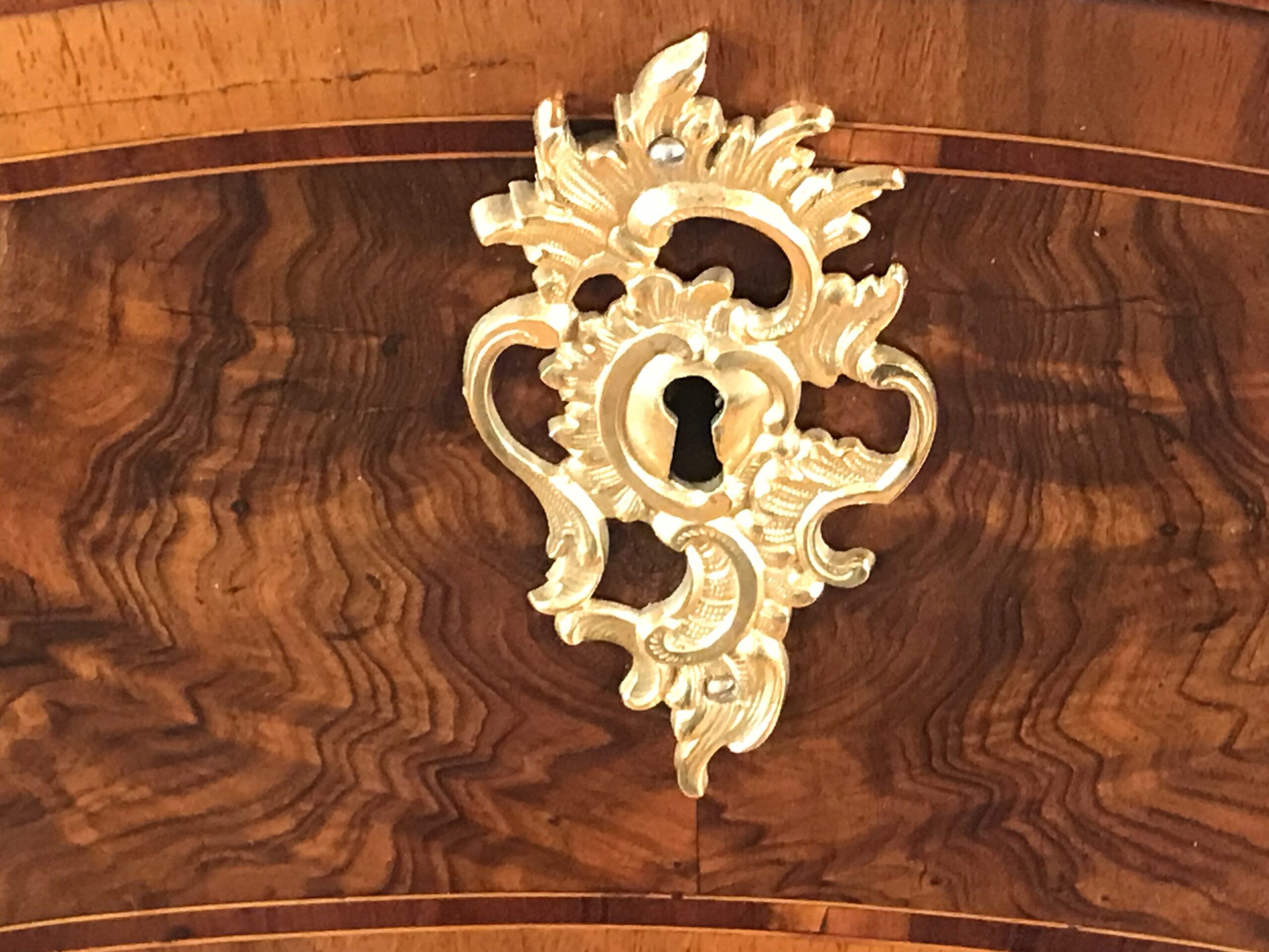 Original 18th century ormolu escutcheons on a German Baroque chest of drawers, highlighting historic craftsmanship and refined design.