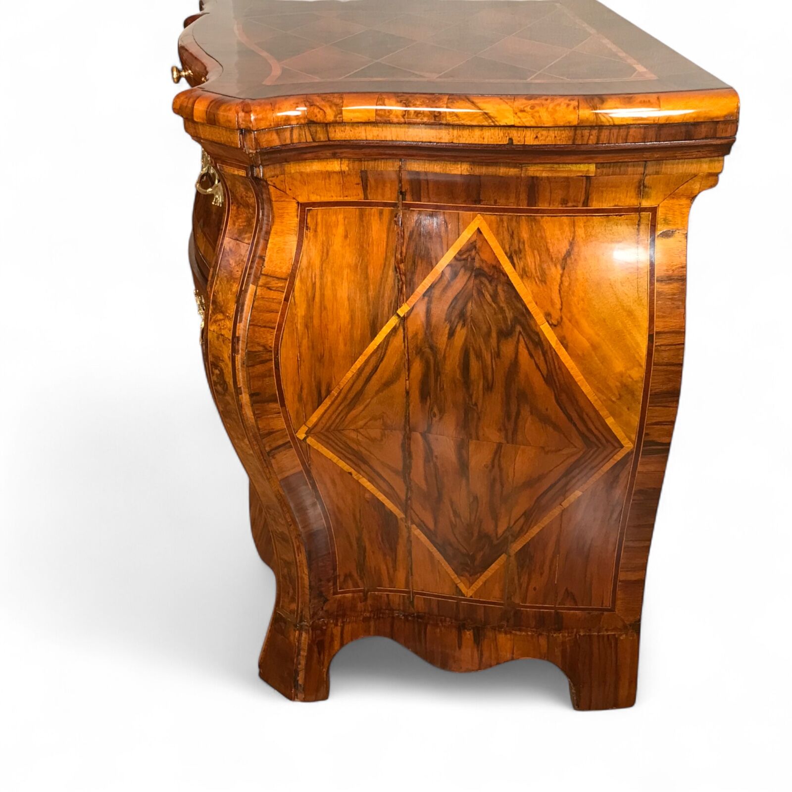 Side view of German Baroque chest of drawers showing large diamond-shaped veneer patterns and elegant bombe silhouette- Styylish
