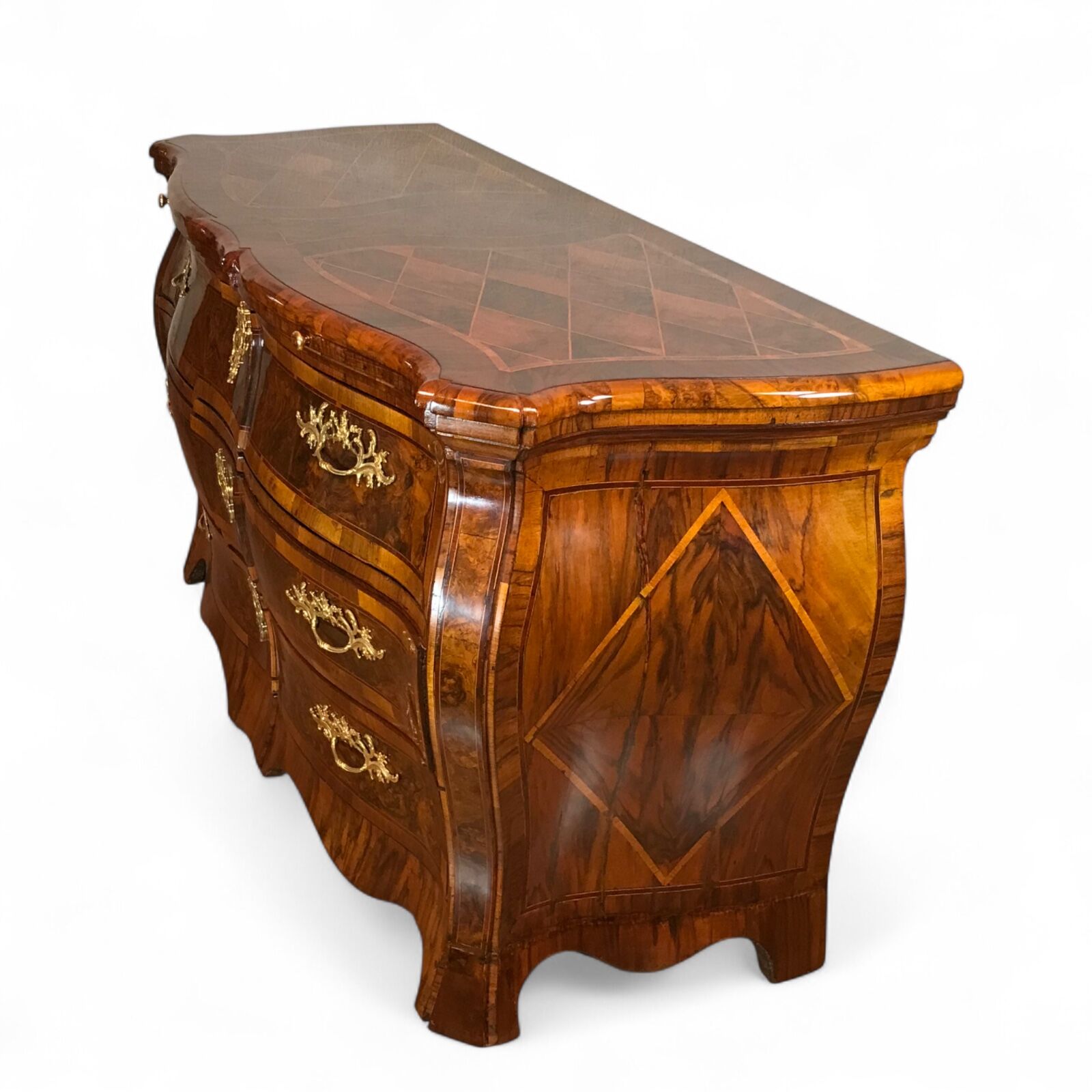 Exquisite 18th century German Baroque chest of drawers (c. 1750) with sculptural bombe silhouette, geometric marquetry, diamond-shaped side motifs, and original 18th century ormolu fittings, viewed from front-right three-quarter angle- Styylish