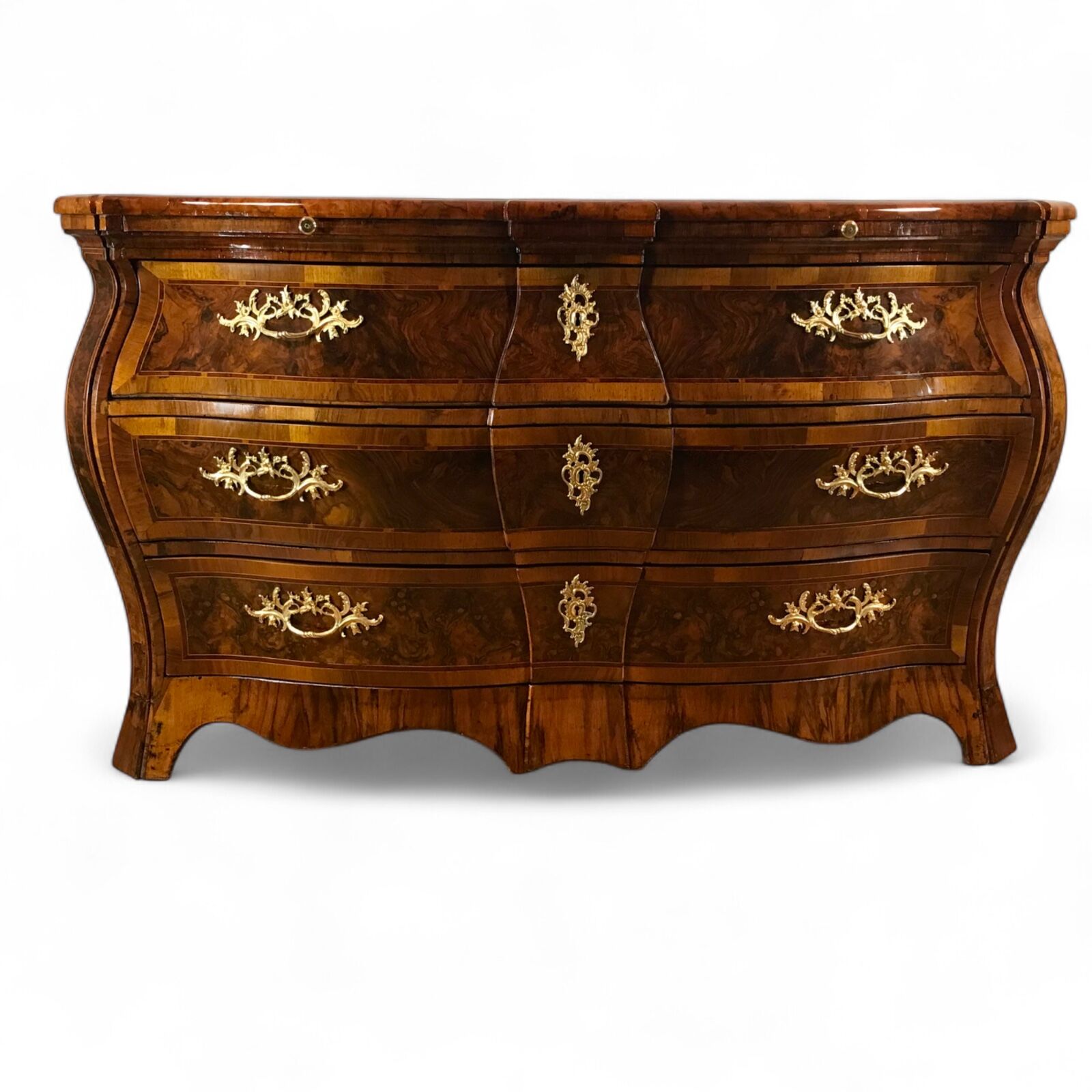 Exquisite 18th century German Baroque chest of drawers (c. 1750) with bombe shape, walnut veneer featuring root walnut accents, intricate geometric marquetry on the top, large diamond-shaped motifs on the sides, three spacious drawers, two pull-out shelves, and original 18th century ormolu fittings. Expertly refinished antique for luxury interiors and collectors- Styylish